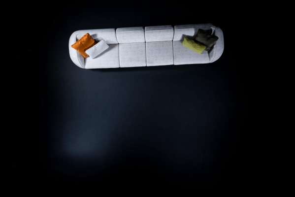 Sofá esquinero moderno de seis plazas en tela acolchada de color gris.