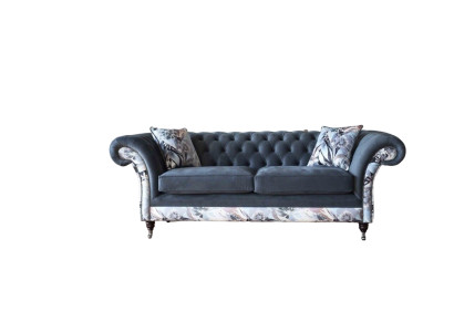 Un llamativo sofá de tres plazas en diseño Chesterfield con delicada decoración de flores grises.
