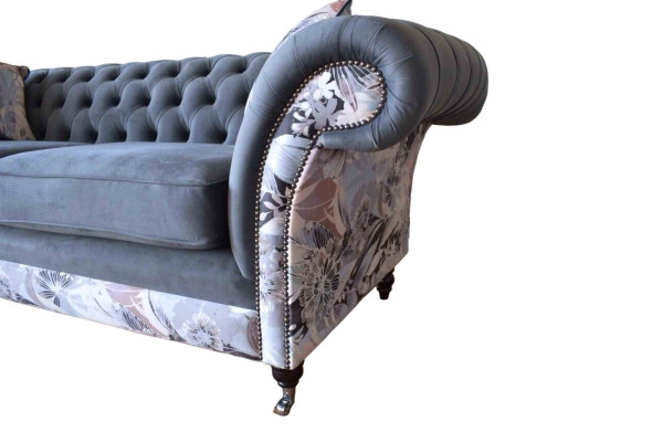 Un llamativo sofá de tres plazas en diseño Chesterfield con delicada decoración de flores grises.