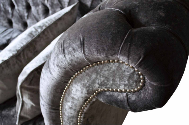 Un lujoso sofá clásico de estilo Chesterfield en un tono plateado profundo.