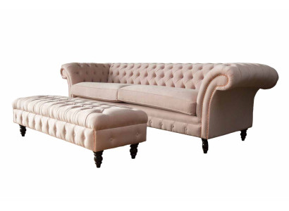 Un lujoso sofá de cuatro plazas de color rosa en diseño Chesterfield, que incluye cojines de asiento.