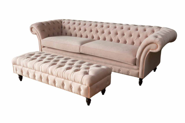 Un lujoso sofá de cuatro plazas de color rosa en diseño Chesterfield, que incluye cojines de asiento.