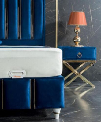 Cama de diseñador azul zafiro con mesitas de noche en patas de acero dorado.