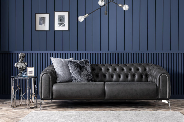 Sofá negro recto de cuatro plazas al estilo Chesterfield para la sala de estar.