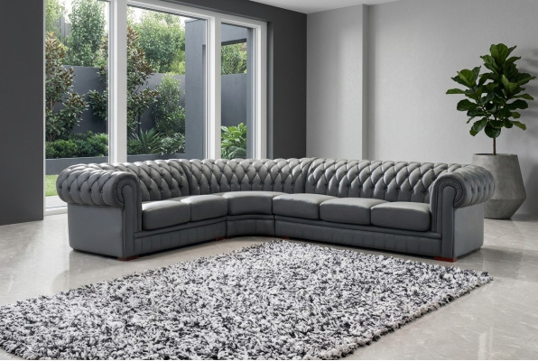 Sofá esquinero clásico Chesterfield tapizado en cuero con decoración de costuras.