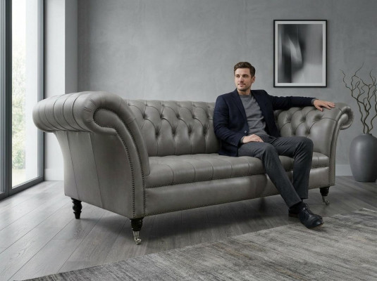 Sofá Chesterfield gris de tres plazas exclusivo para la sala de estar.
