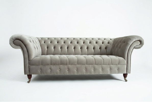 Estiloso sofá Chesterfield de tres plazas de color gris claro para salón de lujo.