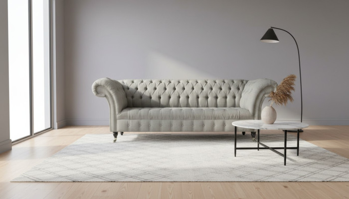 Sofá Chesterfield gris tapizado en tela de cuero y terciopelo.
