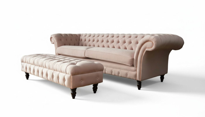 Un lujoso sofá de cuatro plazas de color rosa en diseño Chesterfield, que incluye cojines de asiento.