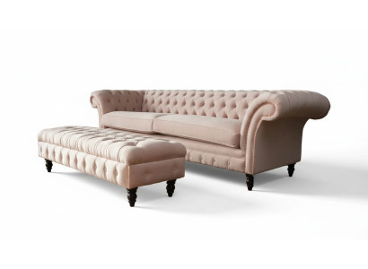 Un lujoso sofá de cuatro plazas de color rosa en diseño Chesterfield, que incluye cojines de asiento.