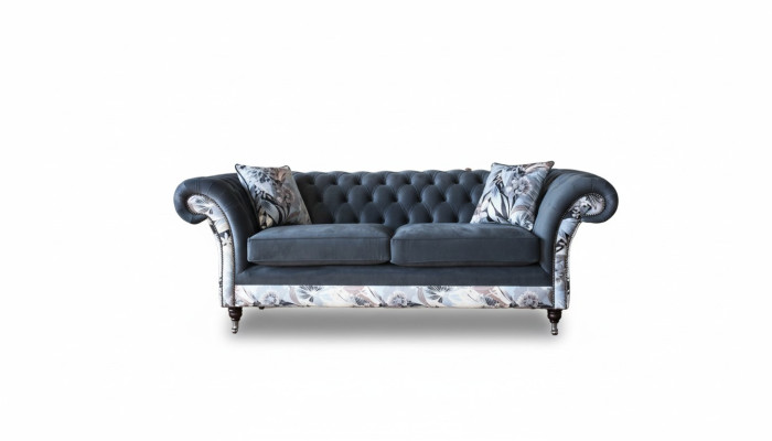 Un llamativo sofá de tres plazas en diseño Chesterfield con delicada decoración de flores grises.