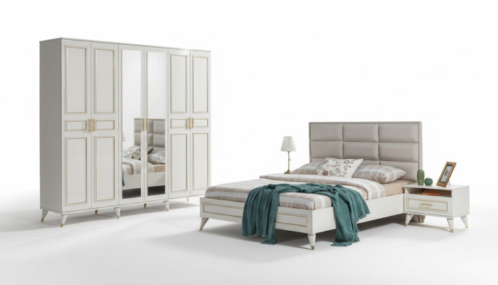 Muebles de dormitorio blancos de madera con armario de vidrio y cama doble de tela con mesitas de noche.